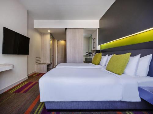 a bedroom with a large white bed and a flat screen tv at Mercure Bangkok Siam in Bangkok