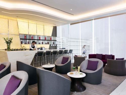 a restaurant with purple chairs and a bar with a man at Mercure Bangkok Siam in Bangkok