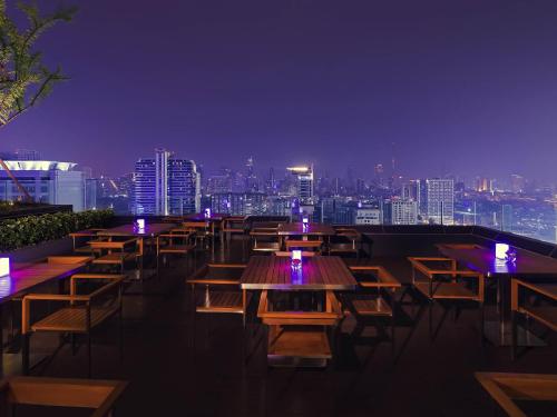 a row of tables and chairs on a rooftop at night at Mercure Bangkok Siam in Bangkok