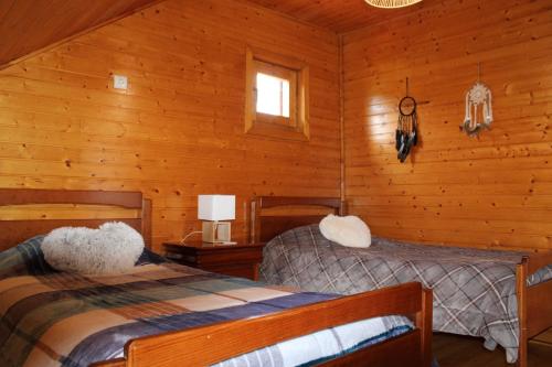 a bedroom with two beds in a log cabin at Chalé Casa das Estrelas MM in Pinhanços