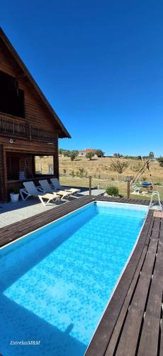 a swimming pool in front of a house at Chalé Casa das Estrelas MM in Pinhanços