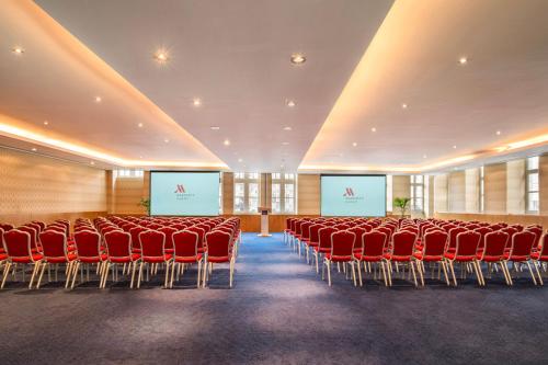 a conference room with red chairs and two screens at Ghent Marriott Hotel in Ghent