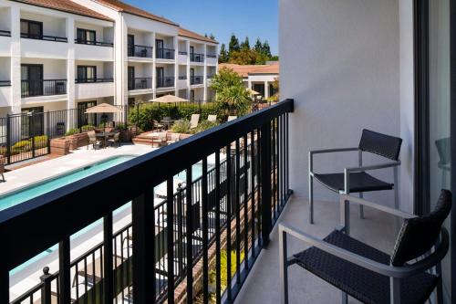 a balcony with two chairs and a swimming pool at Courtyard San Jose Cupertino in Cupertino