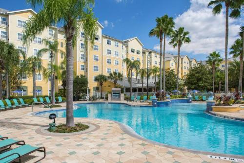 a swimming pool with palm trees in front of a building at Residence Inn by Marriott Orlando at SeaWorld in Orlando