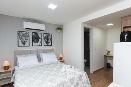 a bedroom with a large bed with white sheets at Estúdio aconchegante no centro de Poços de Caldas in Poços de Caldas