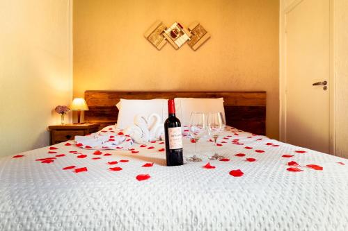 a bottle of wine and glasses on a bed with roses at VELINN Pousada Vila Floratta in Campos do Jordão
