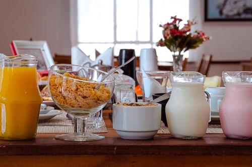 a table topped with glasses of milk and other drinks at VELINN Pousada Vila Floratta in Campos do Jordão