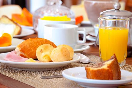 a table topped with plates of bread and orange juice at VELINN Pousada Vila Floratta in Campos do Jordão