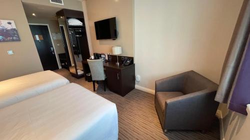 a hotel room with a bed and a desk and a chair at Premier Inn Doha Education City in Doha
