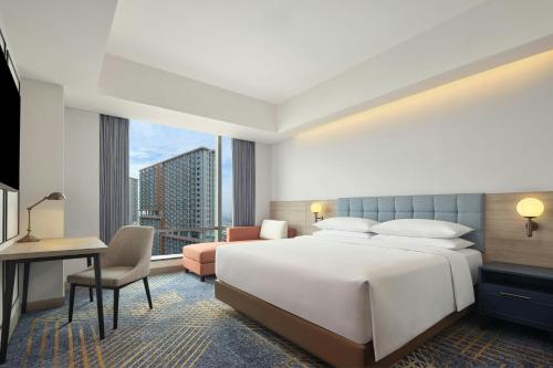 a hotel room with a large bed and a desk at Four Points by Sheraton Bekasi in Bekasi