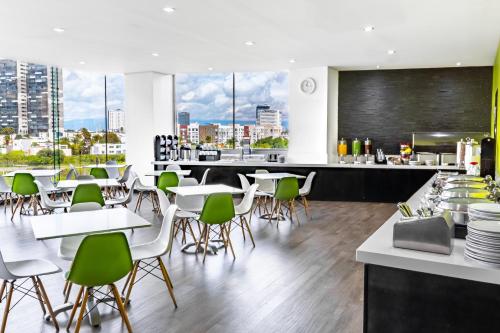 a restaurant with white tables and green chairs at Holiday Inn Express & Suites Puebla Angelopolis by IHG in Puebla