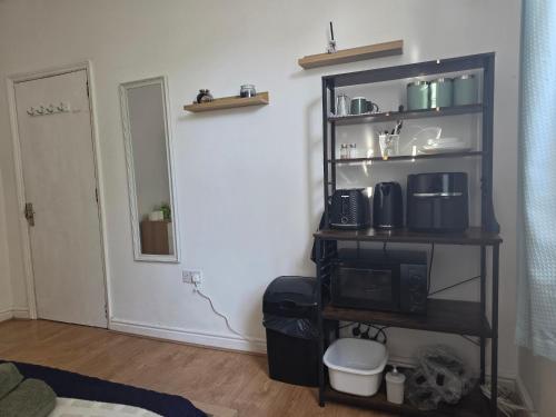 a room with a shelf with a microwave and a door at Studios & Ensuite Doubles - Central RG1 - Oracle - Station & Hospital in Reading