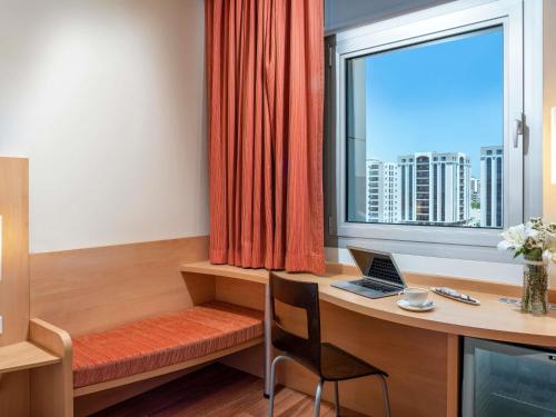 a room with a desk and a window with a laptop at ibis Adana in Adana