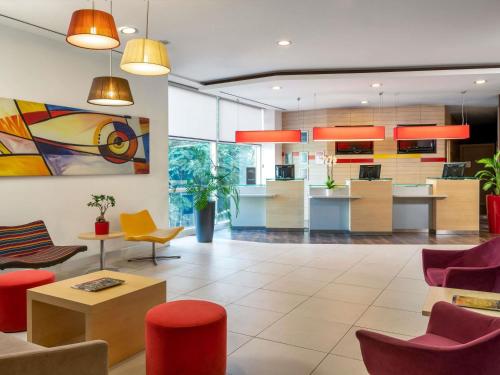 a lobby with chairs and tables and a kitchen at ibis Adana in Adana