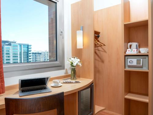 a laptop on a desk in a room with a window at ibis Adana in Adana