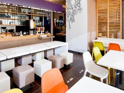a restaurant with white tables and colorful chairs at Ibis Budget Madrid Getafe in Getafe