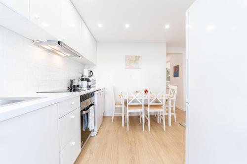 a white kitchen with white cabinets and a table at Artistic 2-bedroom apartment with courtyard in Lisbon