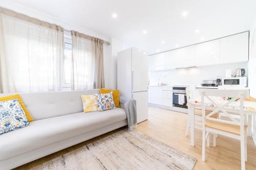 a white living room with a couch and a table at Artistic 2-bedroom apartment with courtyard in Lisbon