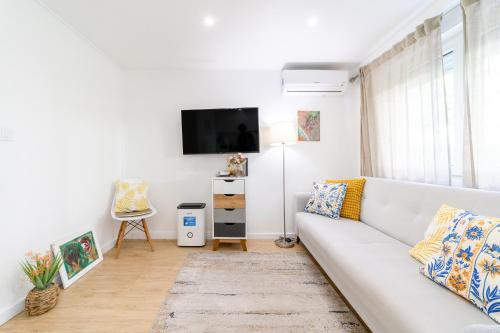 a living room with a white couch and a tv at Artistic 2-bedroom apartment with courtyard in Lisbon