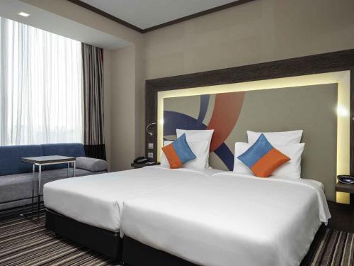 a hotel room with a large white bed with colorful pillows at Novotel Bangkok IMPACT in Nonthaburi