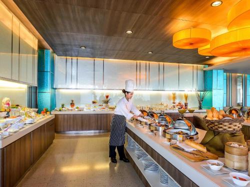 a chef standing in a kitchen preparing food at Novotel Bangkok IMPACT in Nonthaburi