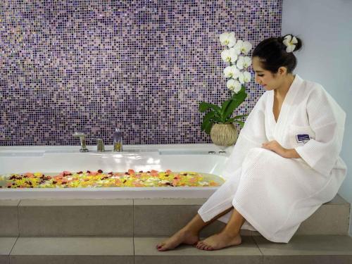 a woman sitting in front of a bath tub at Novotel Bangkok IMPACT in Nonthaburi