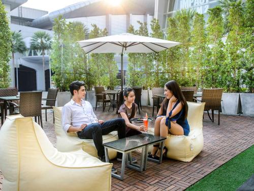 a group of people sitting on chairs under an umbrella at Novotel Bangkok IMPACT in Nonthaburi