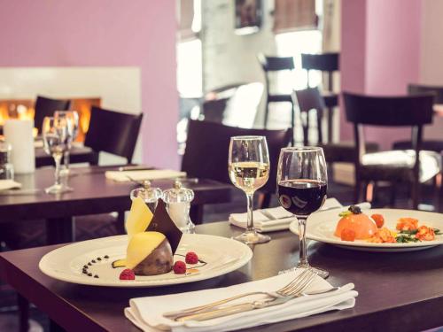 a table with two plates of food and wine glasses at Mercure Nottingham City Centre Hotel in Nottingham