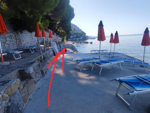 a group of tables and umbrellas next to the water at Locazione turistica Ginestre Mare 