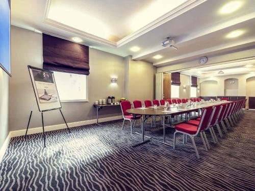 a conference room with a long table and red chairs at Mercure Nottingham City Centre Hotel in Nottingham