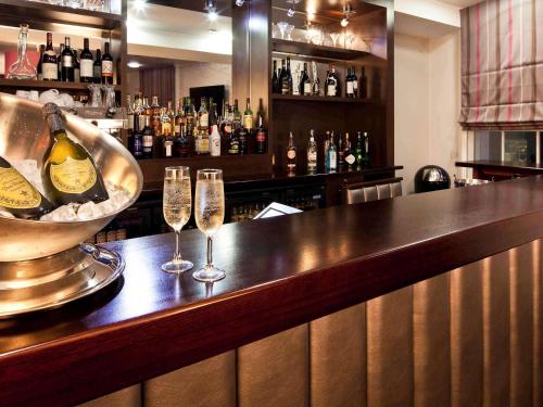 a bar with two glasses of wine and a bottle at Mercure Nottingham City Centre Hotel in Nottingham