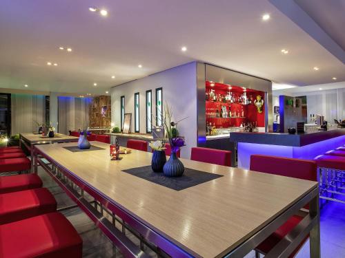 a restaurant with a long table and red chairs at ibis Styles Karlsruhe Ettlingen in Ettlingen