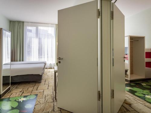 a bedroom with a bed and a door to a room at ibis Styles Karlsruhe Ettlingen in Ettlingen