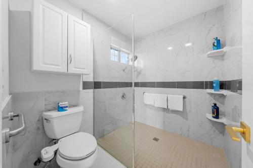 a white bathroom with a toilet and a glass shower at Entire Private 4BR 2Bth, Pool, View, 4 Parking, King Bed, Big Yard in El Cajon