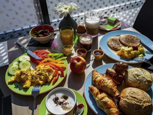 a wooden table topped with plates of food and drinks at ibis Styles Karlsruhe Ettlingen in Ettlingen