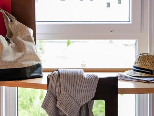 a table with a bag and a hat next to a window at ibis München City Süd in Munich