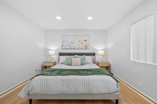 a white bedroom with a large bed and two tables at Entire Private 4BR 2Bth, Pool, View, 4 Parking, King Bed, Big Yard in El Cajon