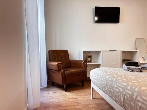 1 dormitorio con silla, 1 cama y TV en Cobalto 2 Quartos Parque Cidade Pet Friendly, en Aveiro