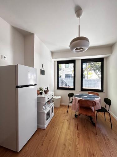 a kitchen with a table and a white refrigerator at Cobalto 2 Quartos Parque Cidade Pet Friendly in Aveiro