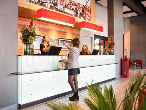 a woman standing at a counter in a restaurant at ibis Leiden Centre in Leiden