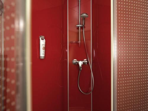 a shower in a bathroom with a red wall at ibis Leiden Centre in Leiden