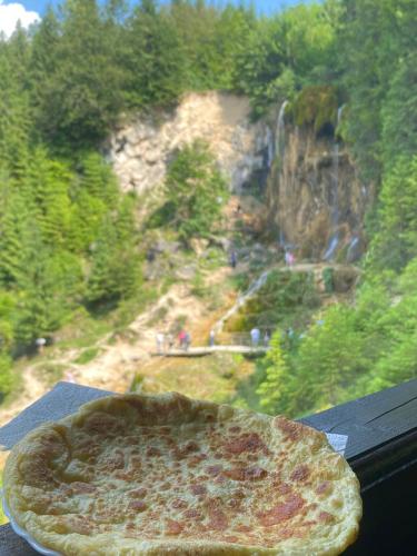 a pizza sitting on a table with a view of a waterfall at Casa de Vacanta Cascada in Vidra