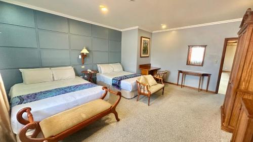 a hotel room with two beds and a chair at Hotel Carvallo in Cuenca
