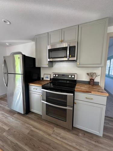 a kitchen with white cabinets and a stainless steel refrigerator at Ashland Bungalow downtown in Ashland