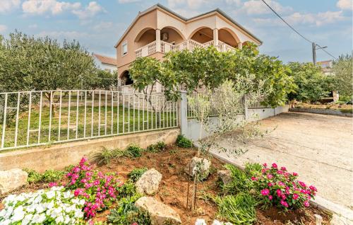 a house with a fence and flowers in a yard at Lovely Apartment In Maslenica With House Sea View in Šarić