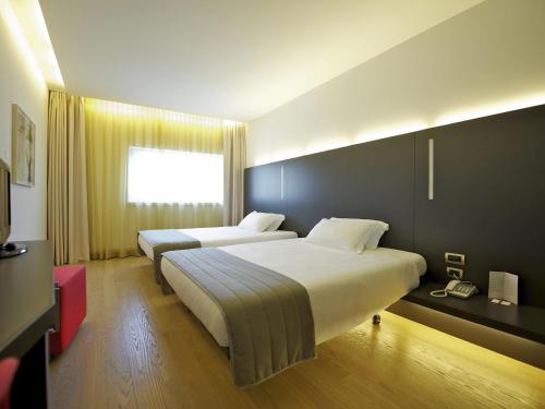 a hotel room with two beds and a window at Mercure Nerocubo Rovereto in Rovereto