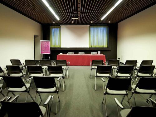 a room with chairs and a table and a podium at Mercure Nerocubo Rovereto in Rovereto