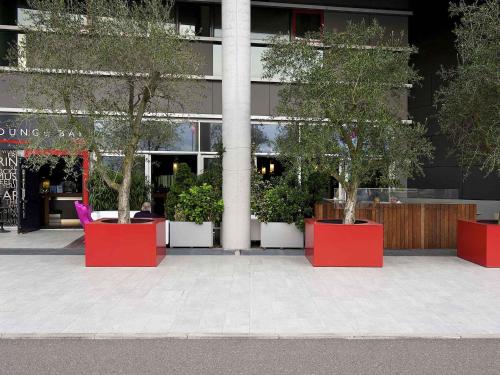a group of trees in red pots in front of a building at Mercure Nerocubo Rovereto in Rovereto