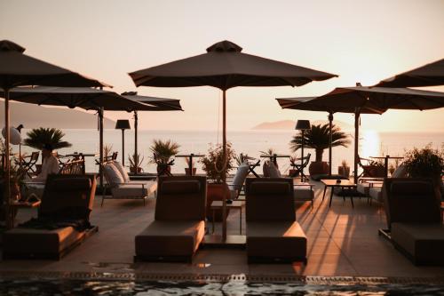 a patio with chairs and umbrellas and the ocean at Magnus Hotel in Vlorë
