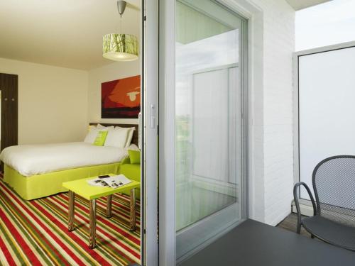 a room with a bed and a sliding glass door at ibis Styles Zeebrugge in Zeebrugge